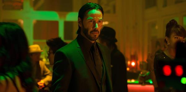 Keanu Reeves standing solemnly as John Wick in John Wick