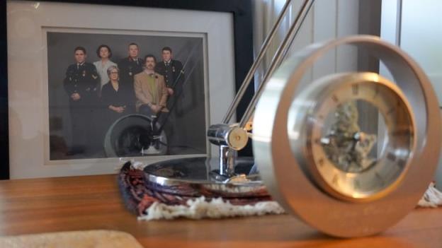 A f<em></em>ramed photo of a group of six people with a desk lamp and clock in the foreground.