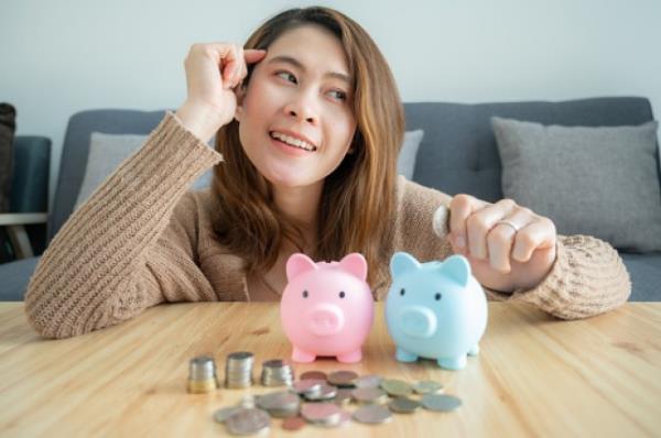 Woman planning a<em></em>bout her financial while putting a coin into piggy bank for saving money.