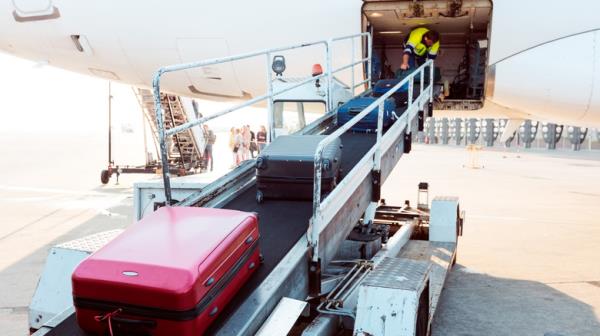 Airport ground crew loading luggage into a passenger plane.